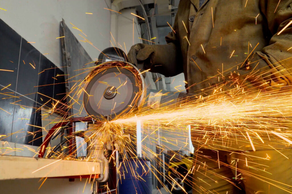 Close-up of a worker using an angle grinder on metal, producing sparks